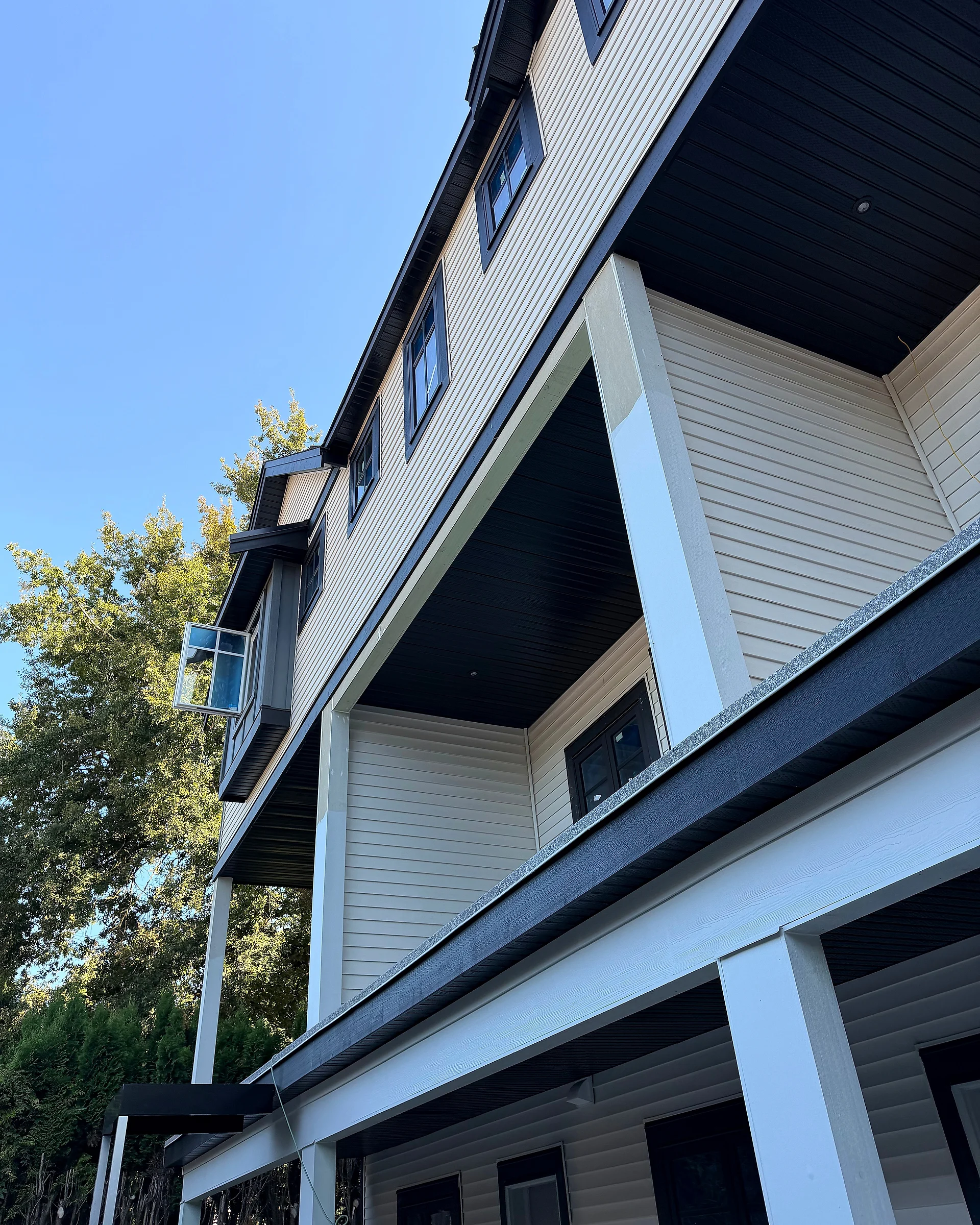 Corner of a townhouse block in cream lap siding with a white column and black soffits, Abbotsford BC