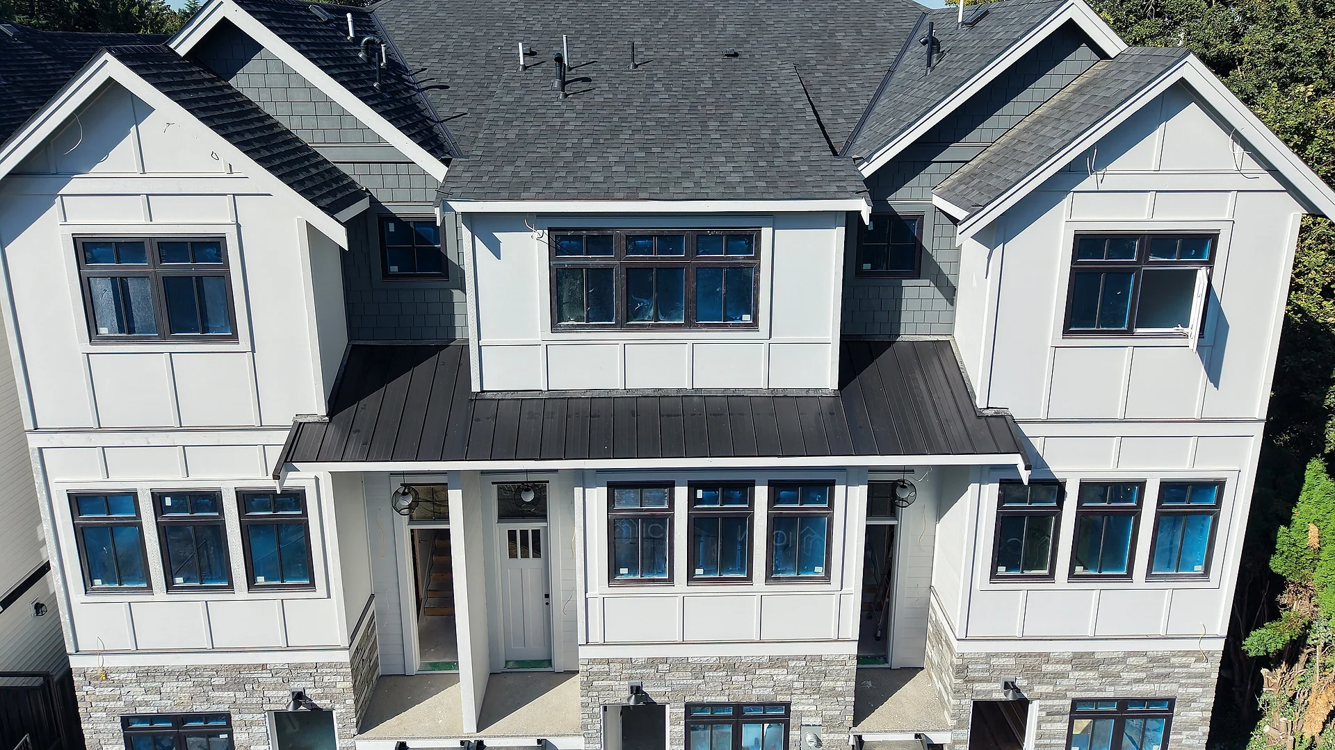 Abbotsford townhouse block in white board and batten and panel over a stone base, from the air — siding by Moonrise Construction