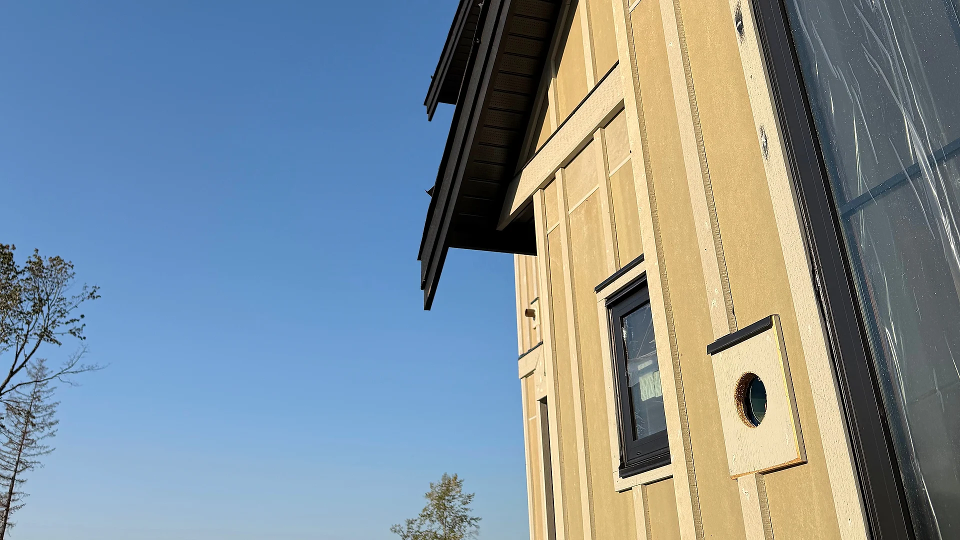 Board-and-batten custom home with Fraser Valley fields and mountains behind, Langley BC — exterior finishing by Moonrise Construction
