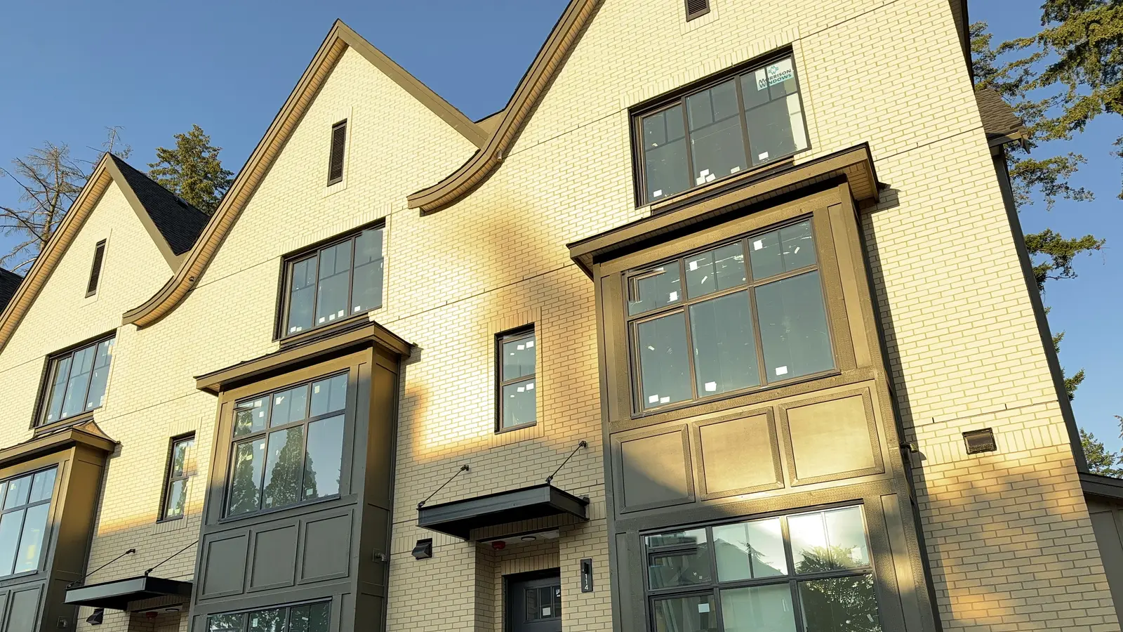 Brick and olive-panel townhouse row at golden hour, exterior finishing by Moonrise Construction, South Surrey BC