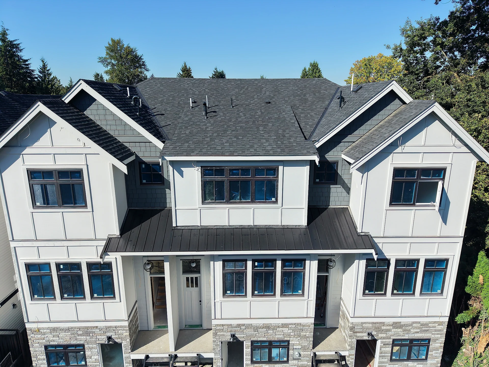 Street-side townhouse block at an angle, white board and batten with shake gables and black trim, Abbotsford BC