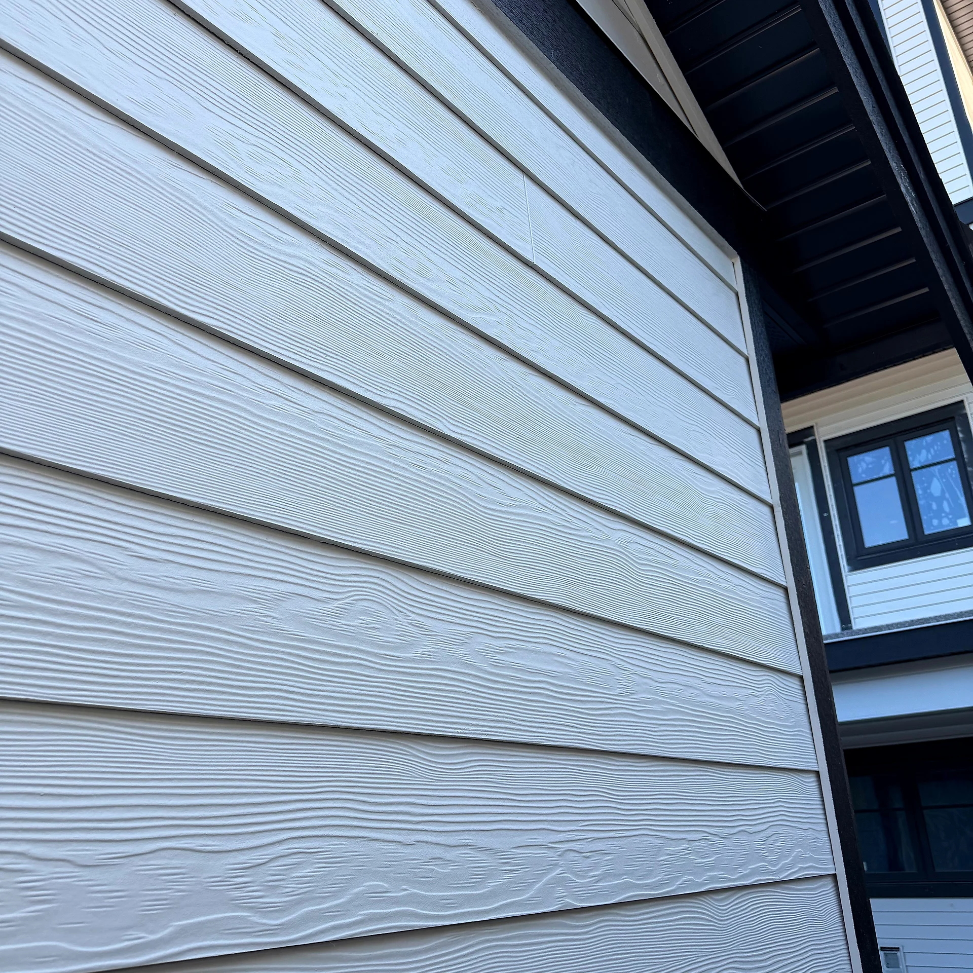 Cream lap siding running up to the dormers and black eave, close-up, Abbotsford BC