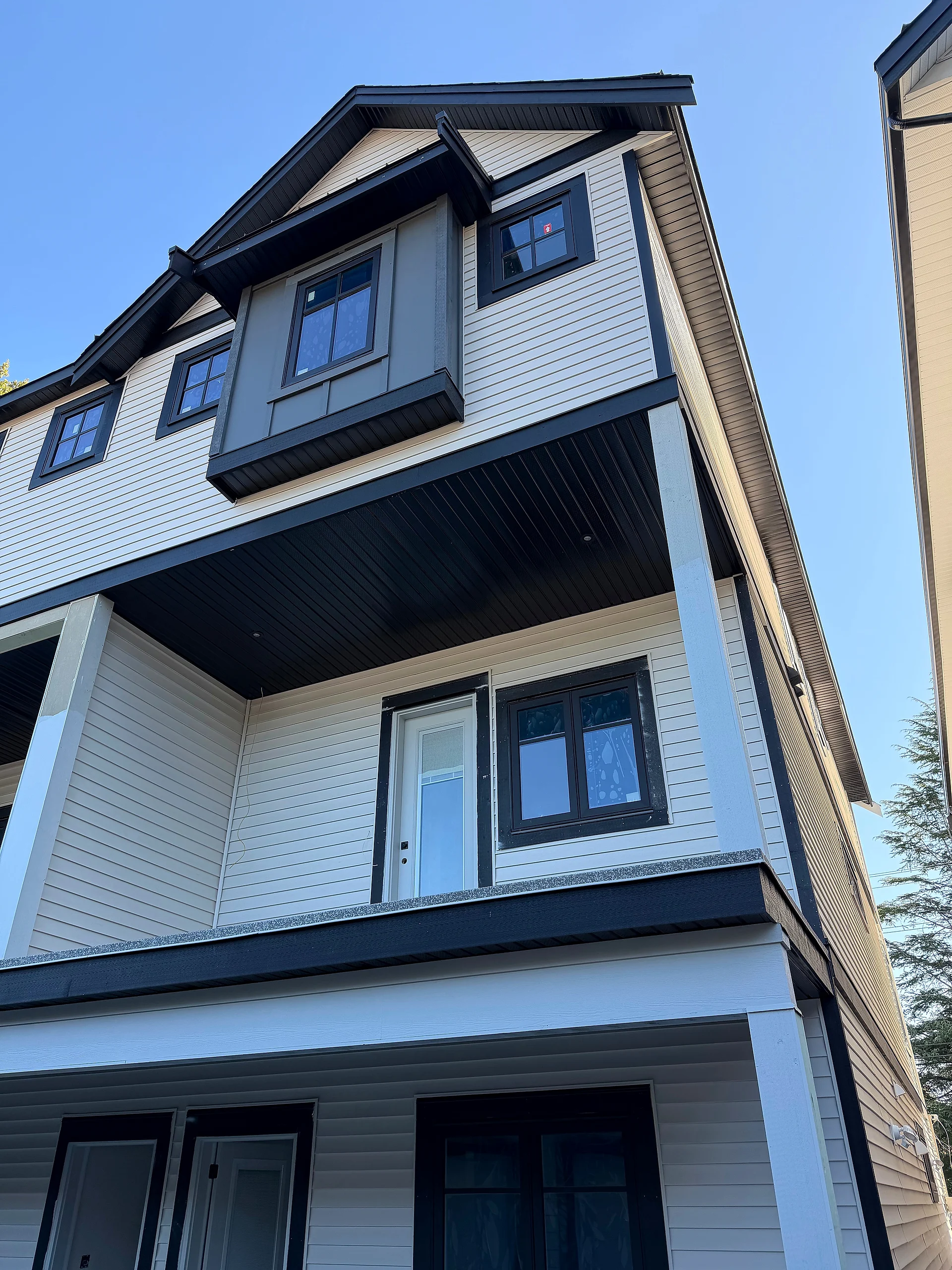 End unit of the rear block, grey panel dormer over cream lap siding and a black soffit, Abbotsford BC