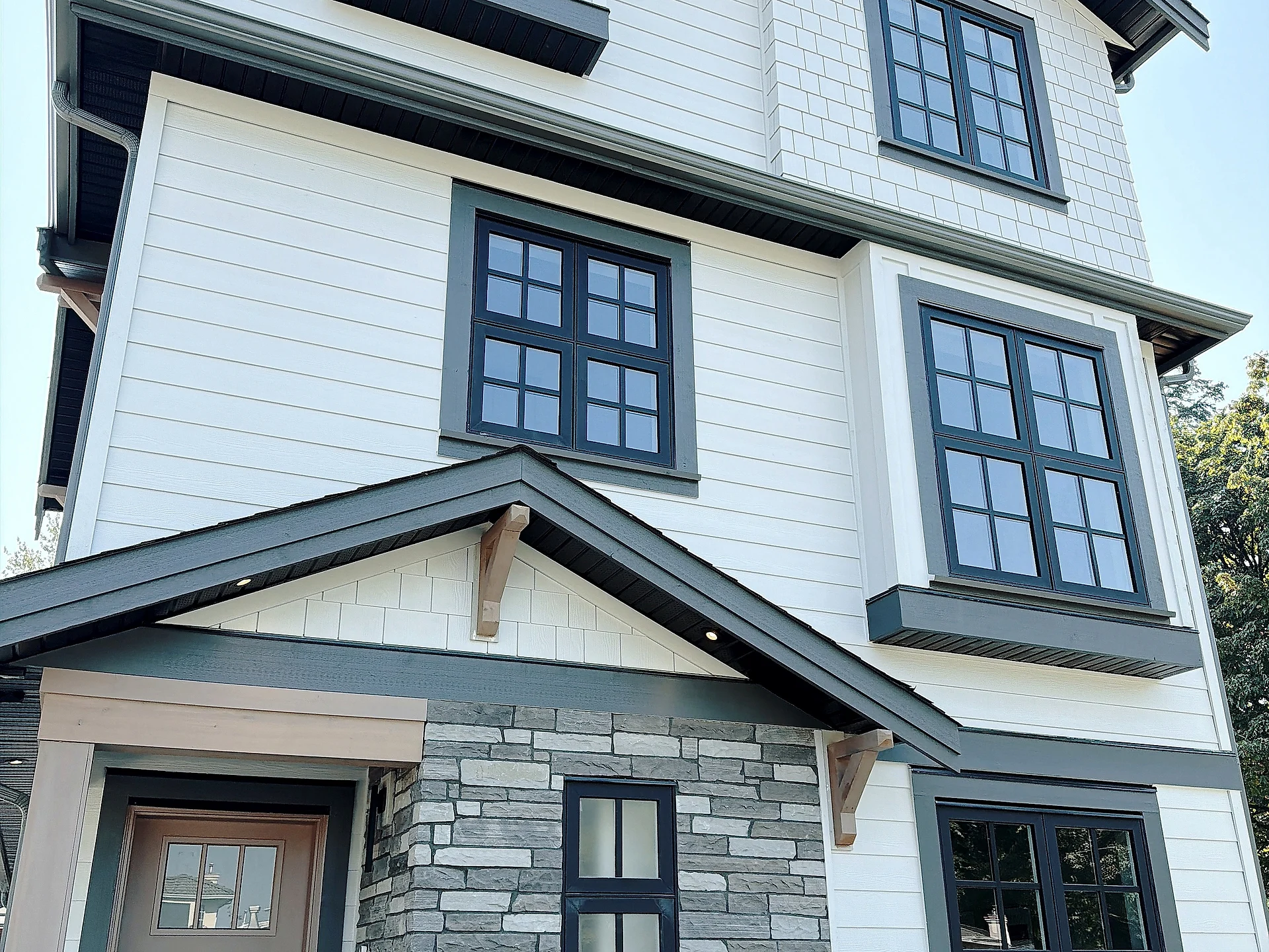 Entry porch with stone-veneer base, white lap siding and timber brackets, Burnaby BC