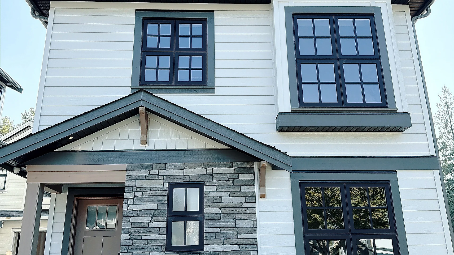 Three-storey home in white Hardie lap and shake over a stone-veneer base, Burnaby BC — exterior finishing by Moonrise Construction