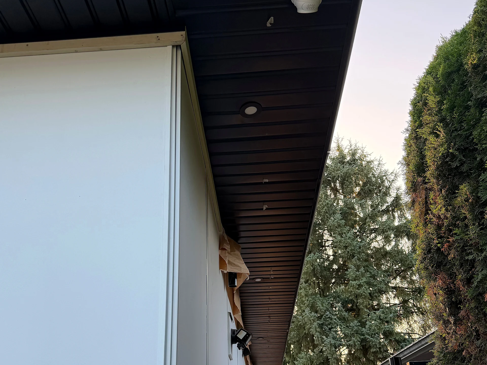 Side passage with smooth white panel and black ribbed metal soffit at sunset, Coquitlam BC