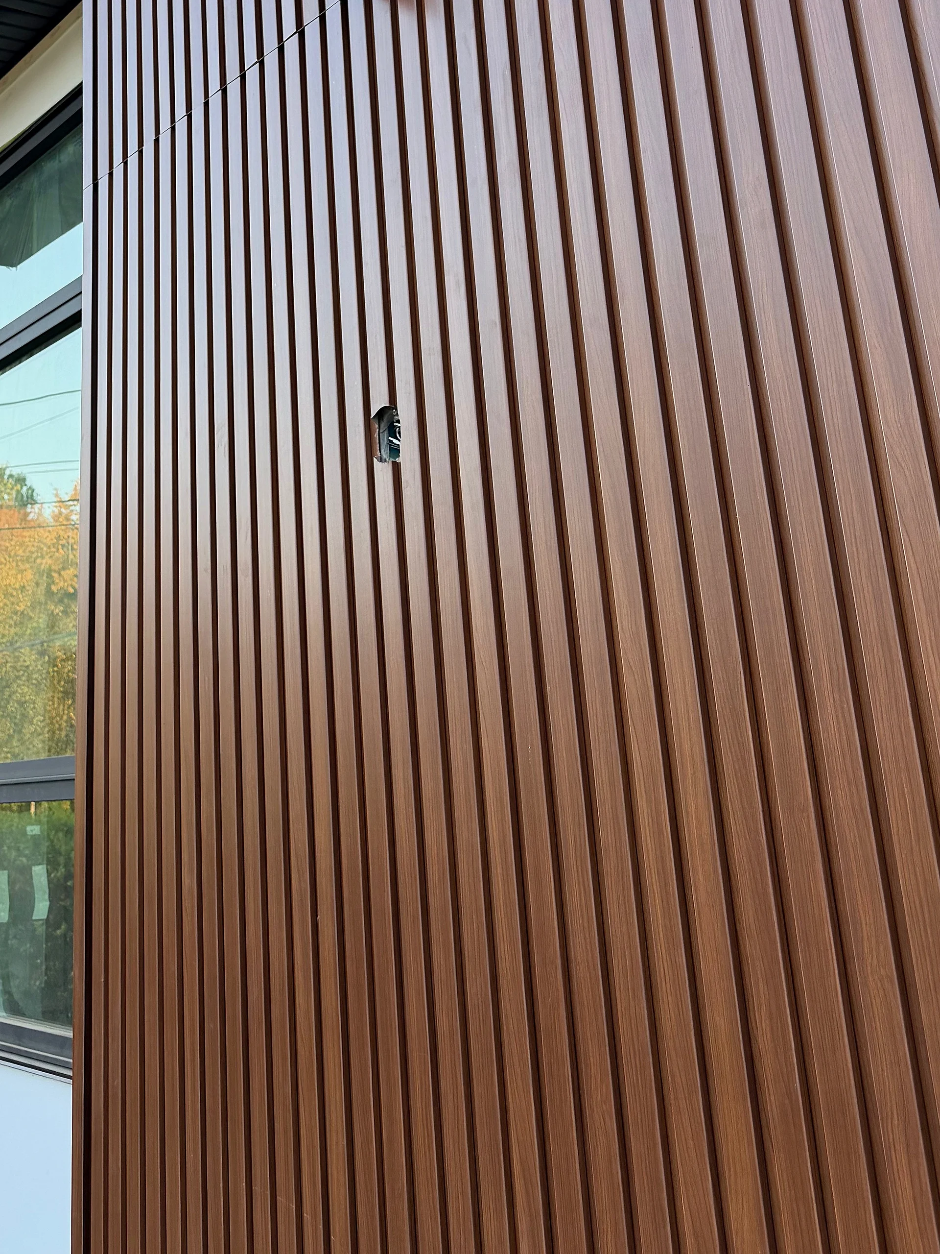 Fluted wood-look cladding wrapping the front corner beside a black-framed window, Coquitlam BC