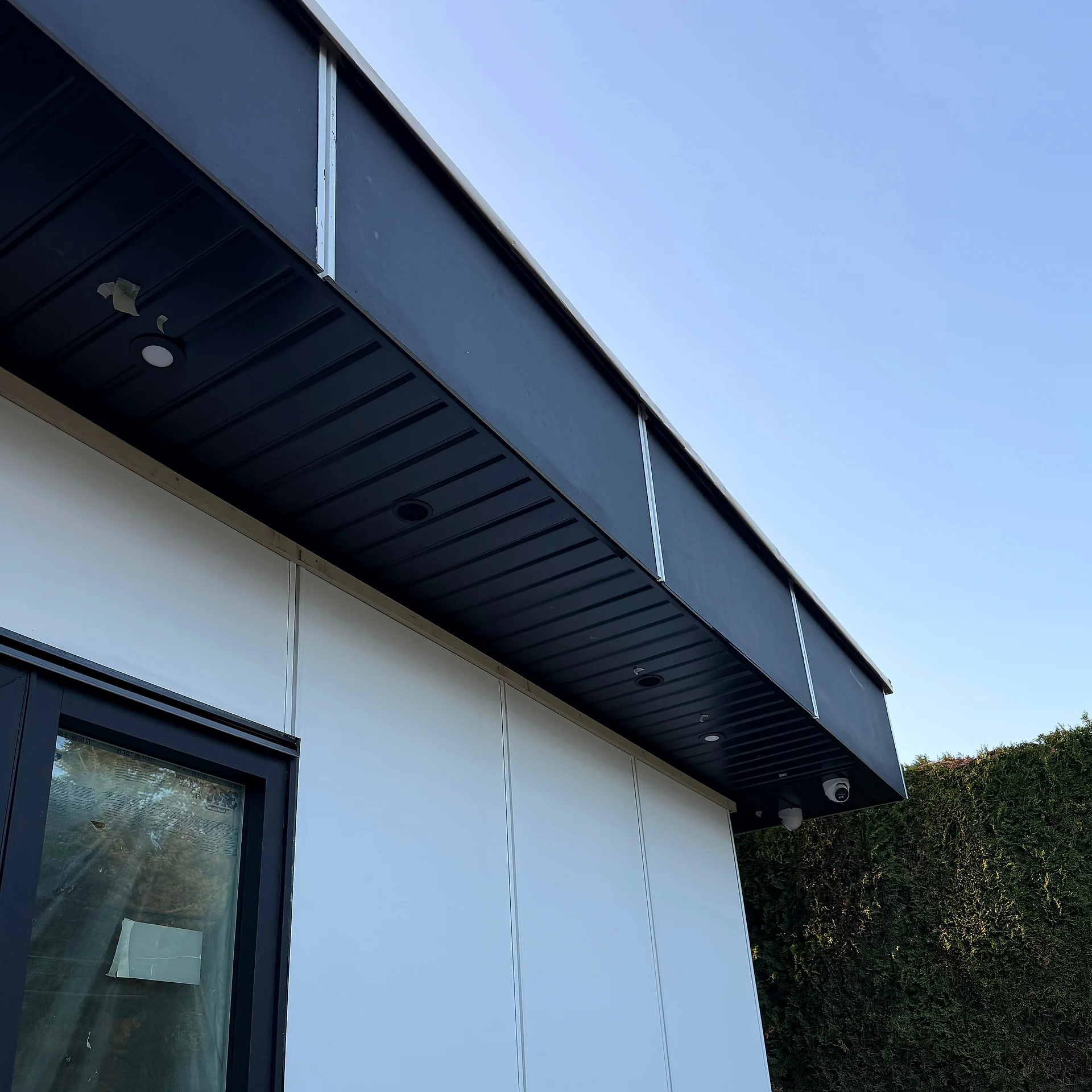 Side door and window in white panel cladding under a black soffit, Coquitlam BC