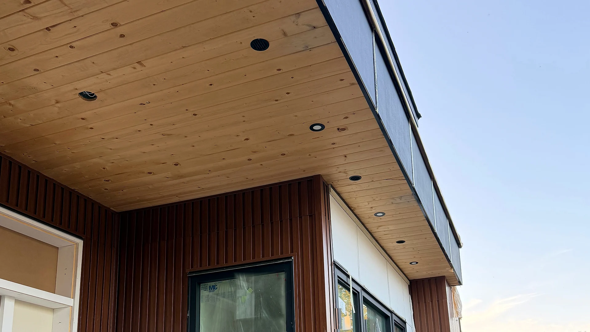Modern home entry with a wood tongue-and-groove ceiling, fluted cladding and black fascia, Coquitlam BC — exterior finishing by Moonrise Construction