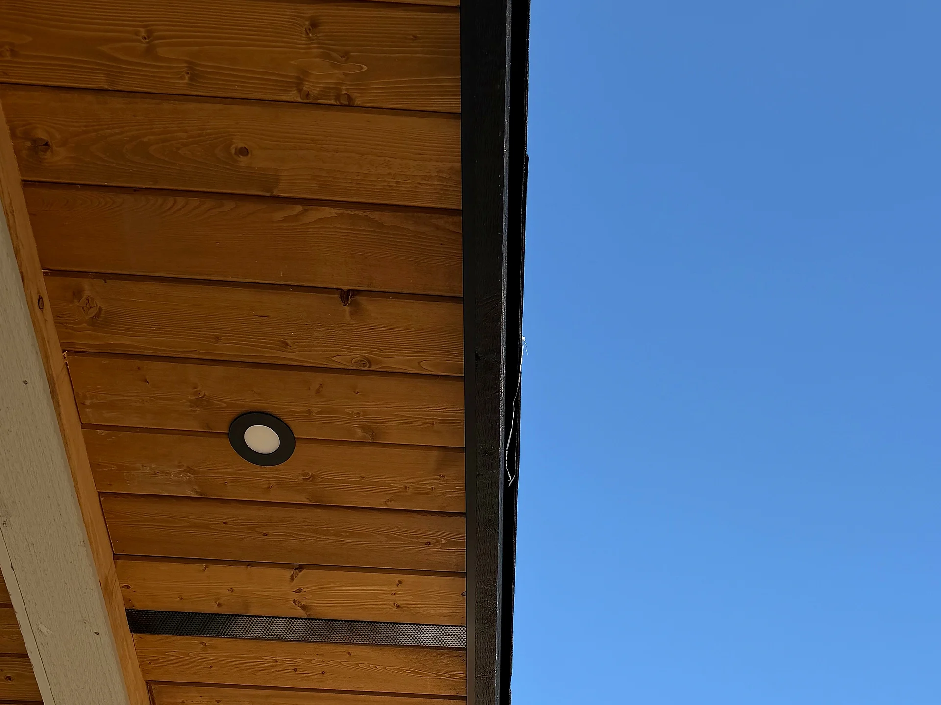 Clear cedar eave soffit and black fascia at the corner of a Langley custom home