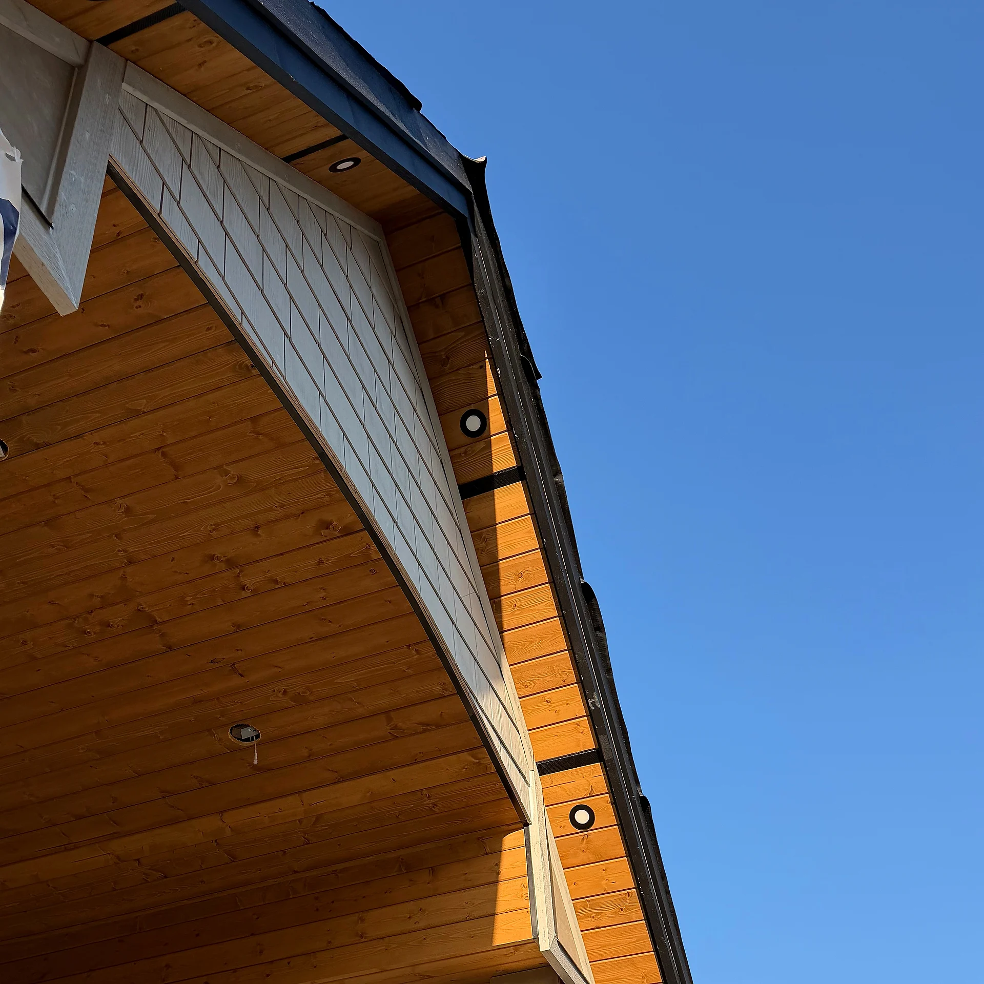 Clear cedar tongue-and-groove porch soffit rising into a shake gable return with recessed lights, Langley BC