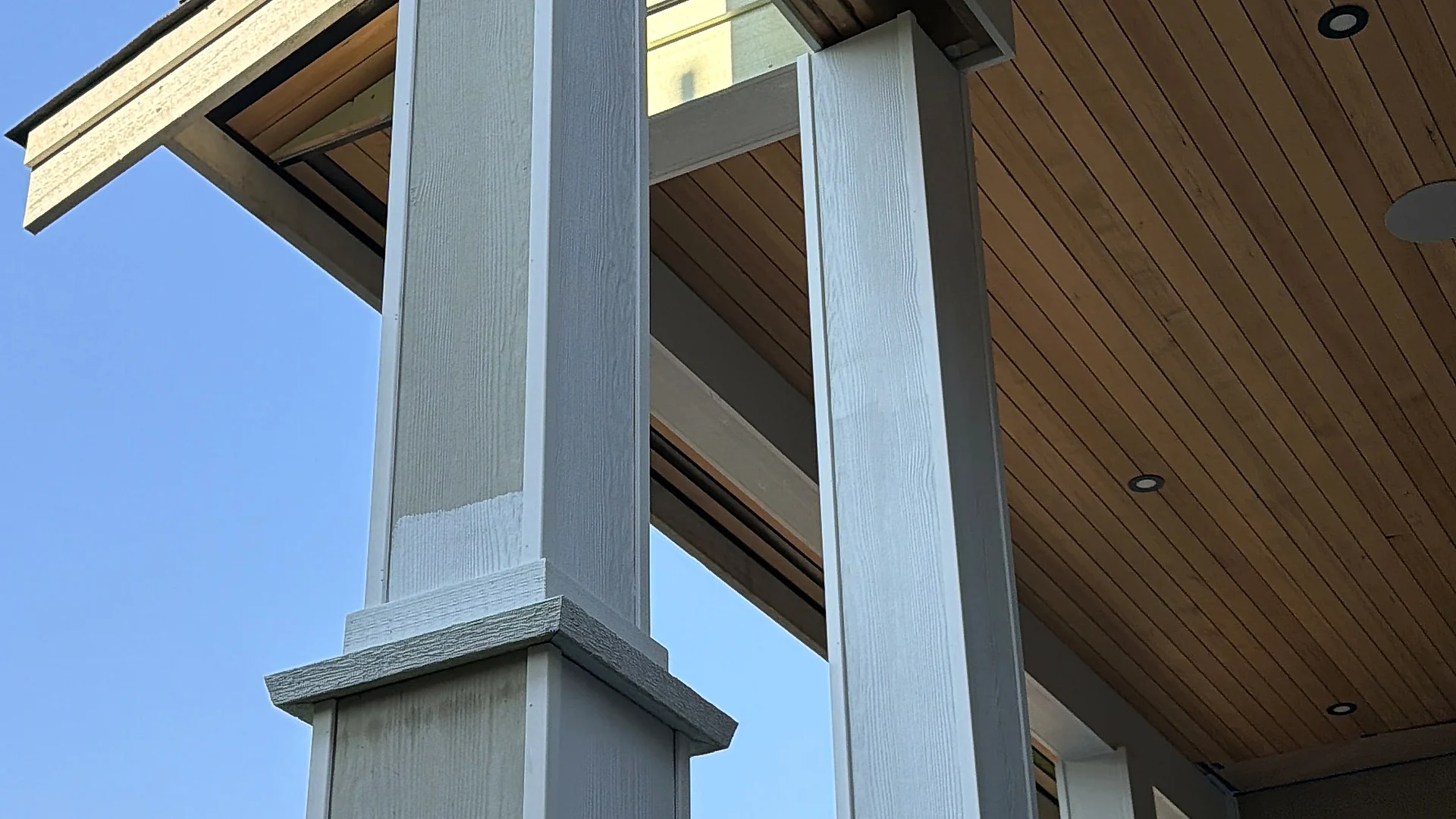 Tapered white craftsman columns under a clear cedar tongue-and-groove porch ceiling, North Vancouver BC — cedar woodwork by Moonrise Construction