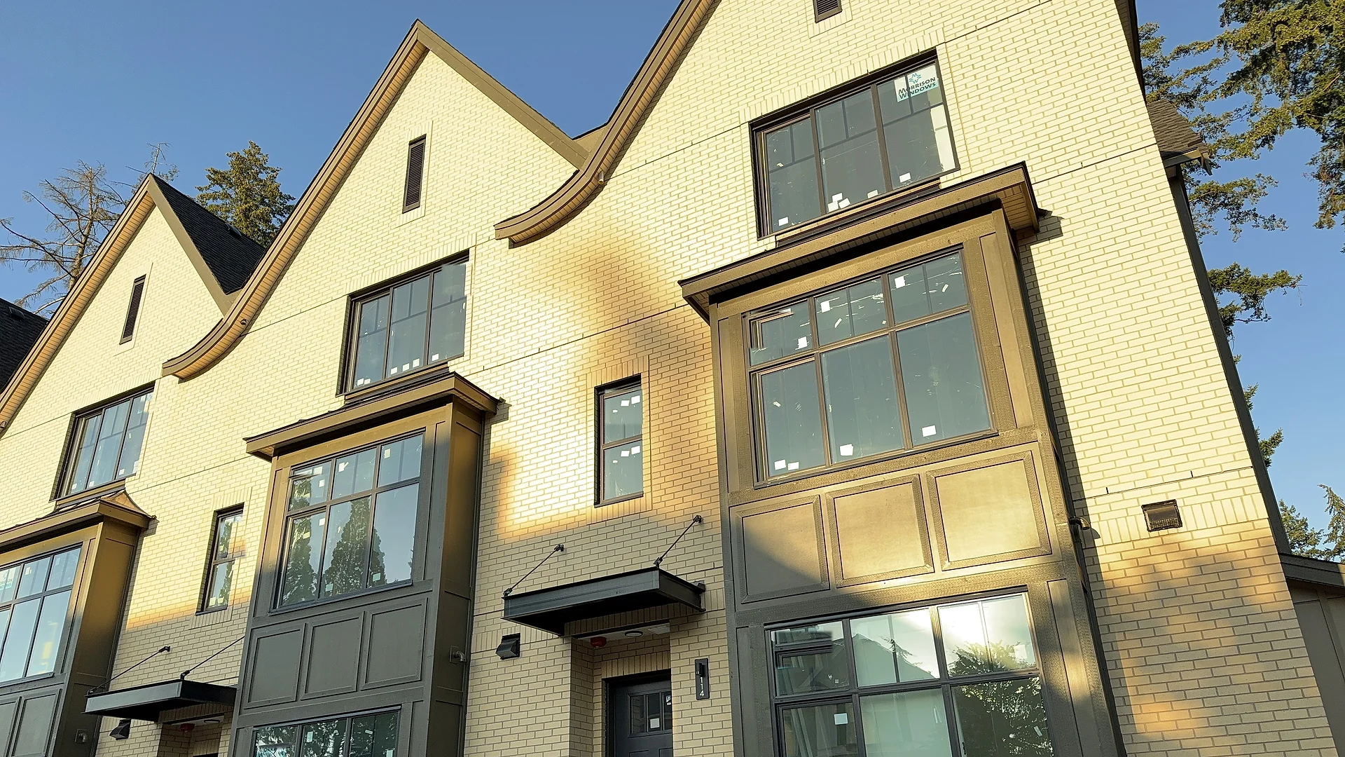 Brick townhouse row with panel bays and black entry canopies at golden hour, South Surrey BC — exterior finishing by Moonrise Construction