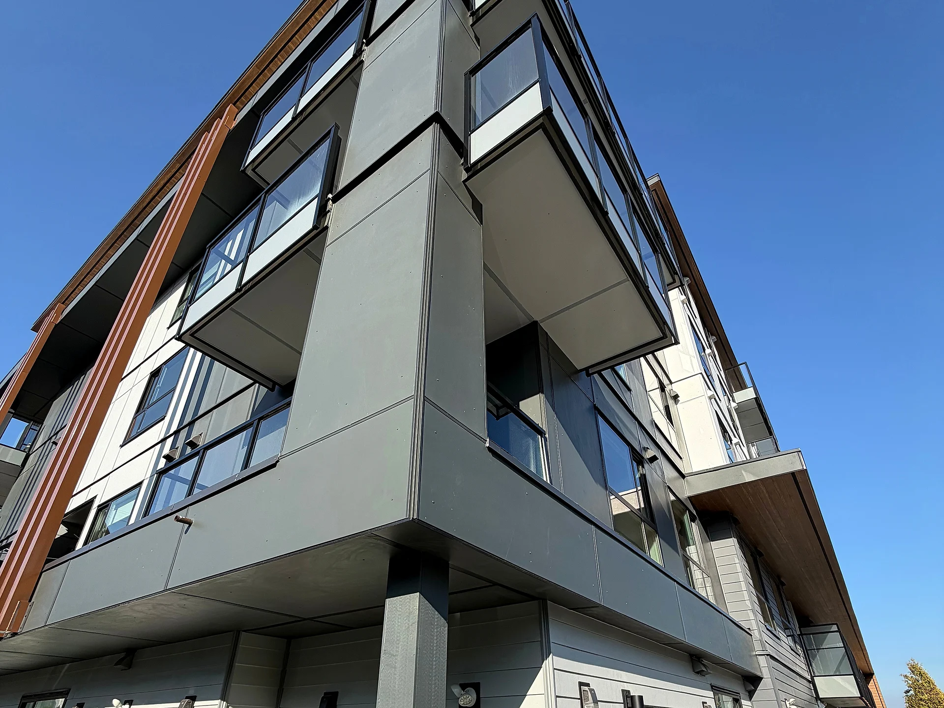 Mid-rise corner from below with wood fins and hydrangeas, South Surrey BC