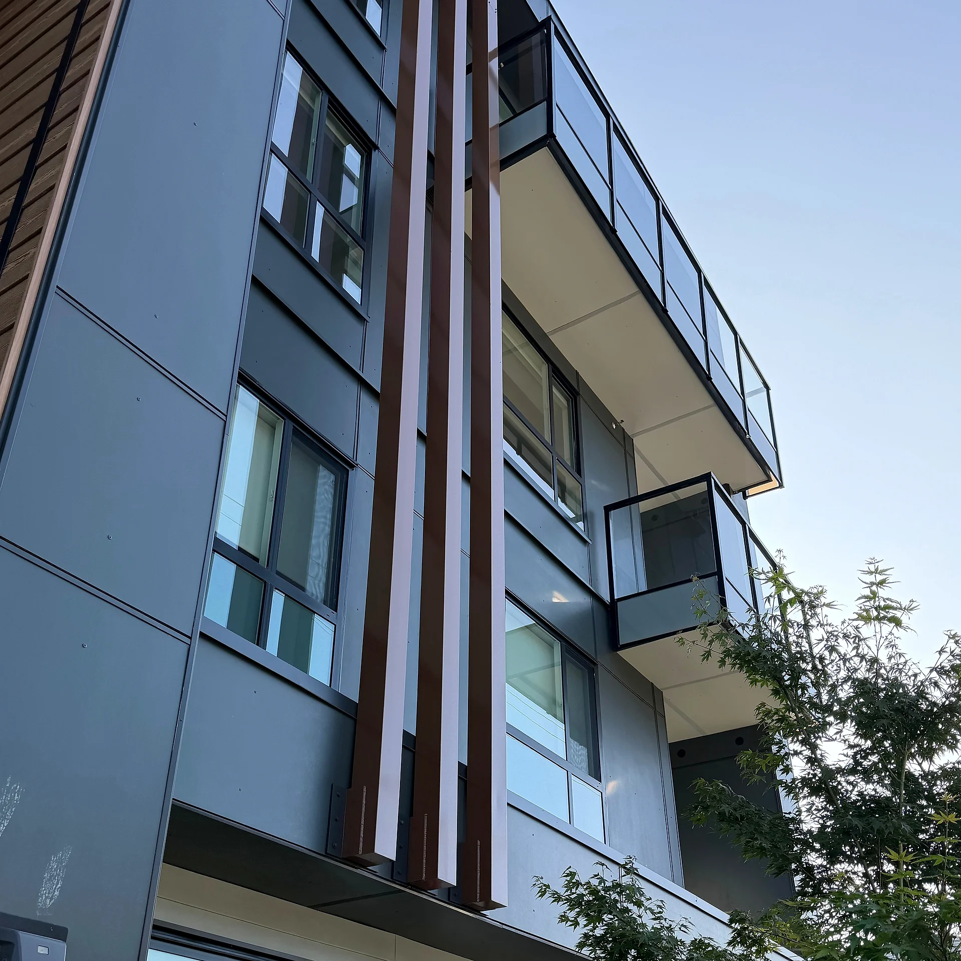 Mid-rise corner with vertical wood fins over white panel, South Surrey BC