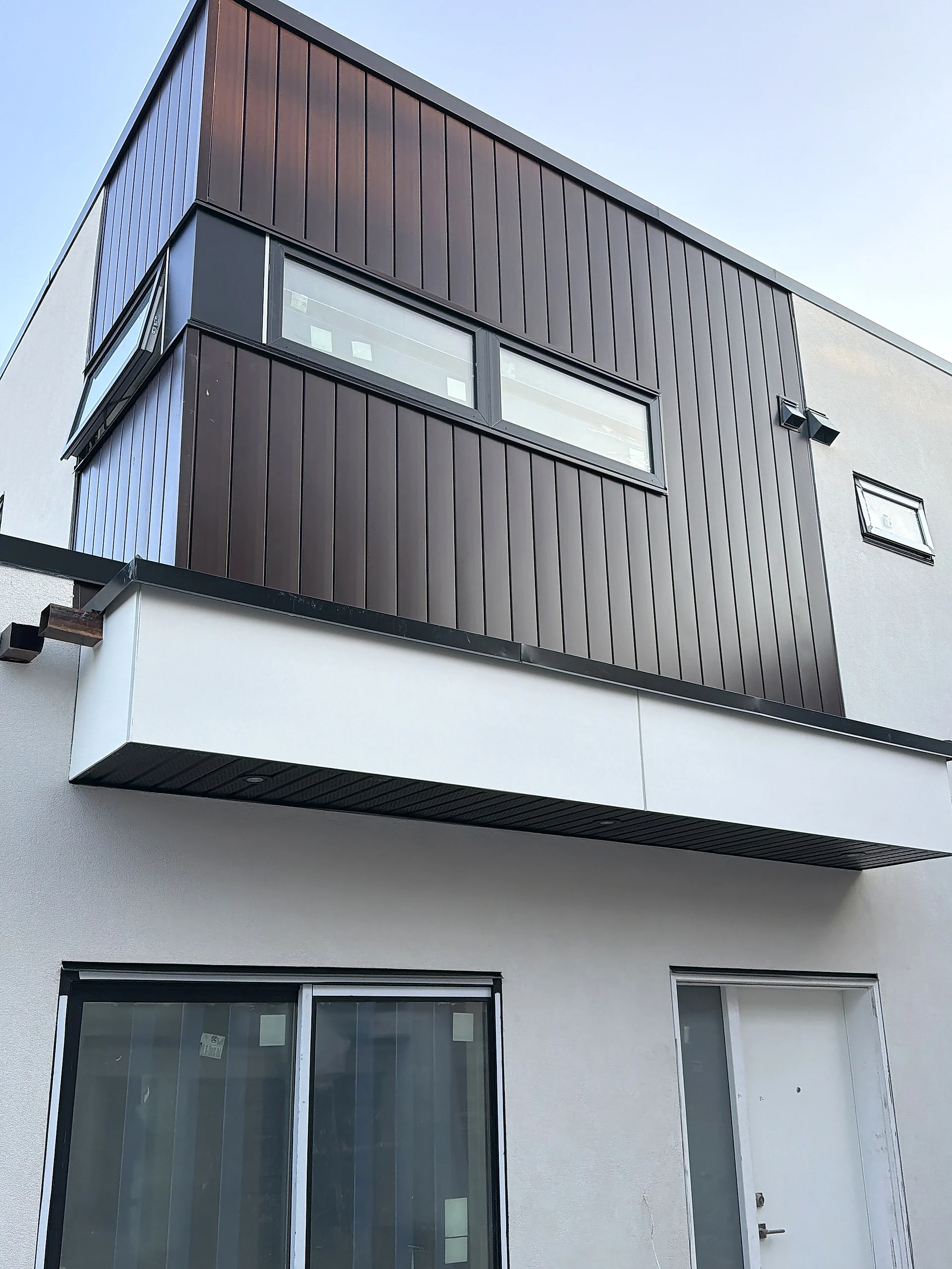 Dark vertical-cladding upper volume over a white panel base, Vancouver BC