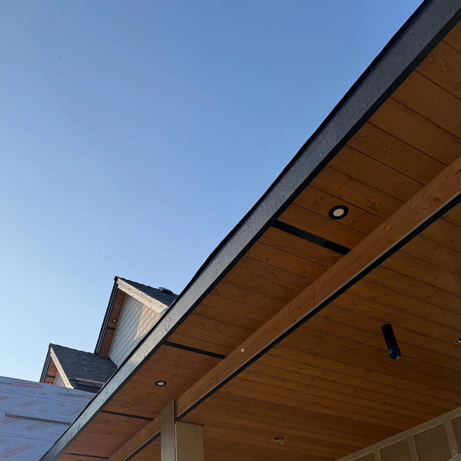 Clear cedar tongue-and-groove porch soffit with recessed lights over square columns, Langley BC