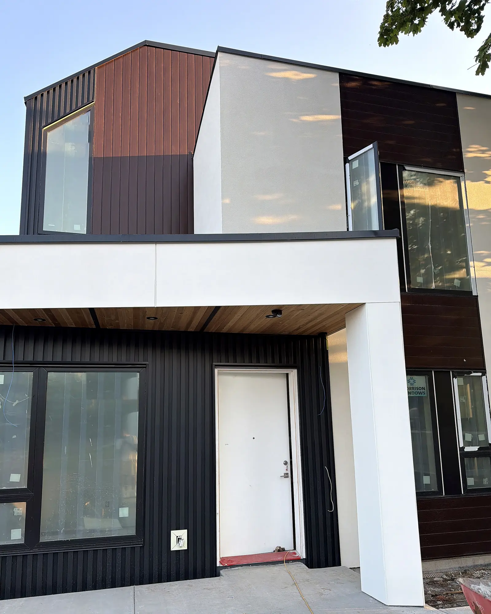 Modern home exterior with black vertical cladding, white panel and a cedar entry soffit, Vancouver BC