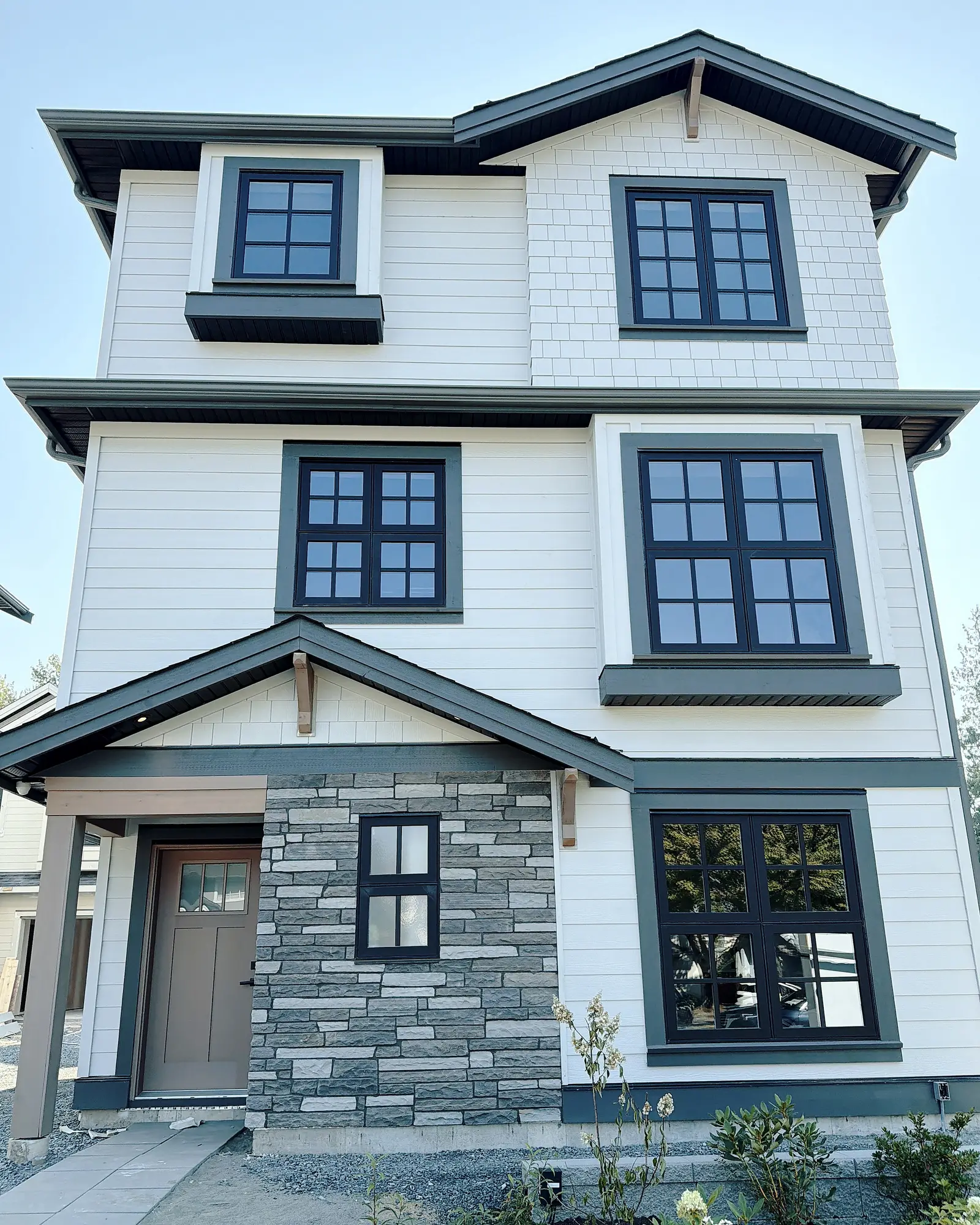 Three-storey home with white Hardie lap siding, shake gables, stone-veneer base and timber brackets, Burnaby BC