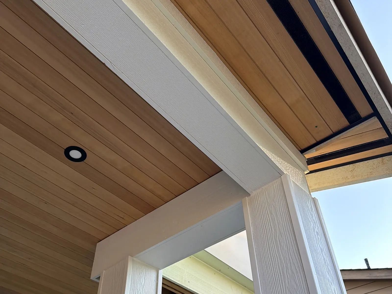 Cedar tongue-and-groove porch ceiling with recessed lighting and a white wrapped beam, North Vancouver BC